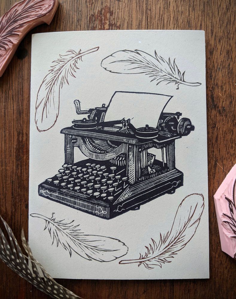 A linocut card of a vintage typewriter surrounded by repeated stamps of goose feathers