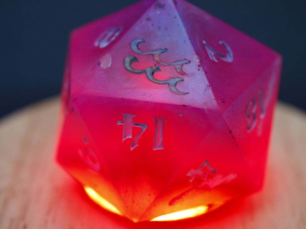 A d20 lit from below with a reddish-orange light making it look on fire, with the symbol for aquarius inlaid in the top face in wood