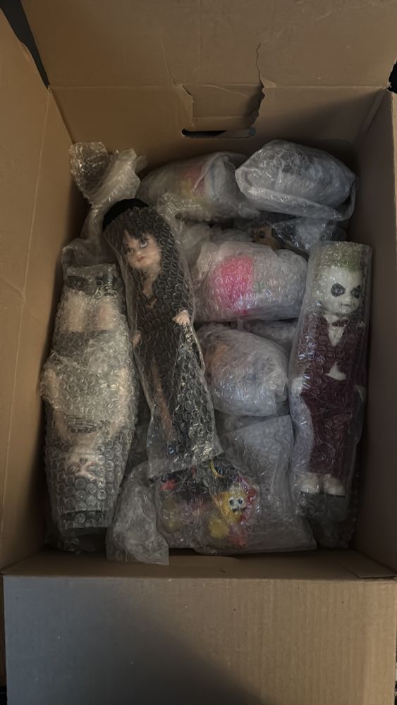 various by bubbles wrapped dolls. visible are elvira living dead doll and beetlejuice living dead doll 