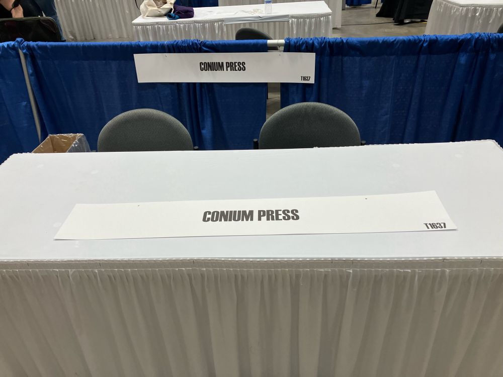 Photo showing an empty table with a sign that reads “Conium Press”