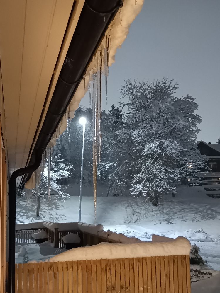 Caramells de gel penjant de la teulada d'una casa.