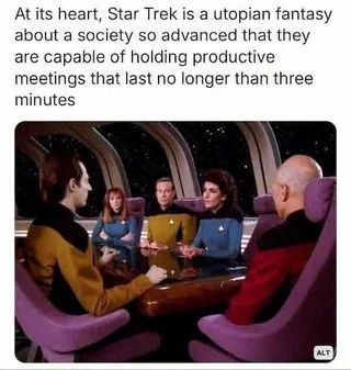 At its heart, Star Trek is a utopian fantasy about a society so advanced they are capable of holding productive meetings that last no longer than three minutes.

Below this text is an image of a scene from Star Trek: The Next Generation showing the main crew gathered around a conference table in a meeting room. The characters are wearing their distinctive colored Starfleet uniforms—yellow, blue, and red—and appear to be engaged in a discussion or briefing. The setting has the characteristic futuristic design of the Enterprise's interior with curved walls and ambient lighting.