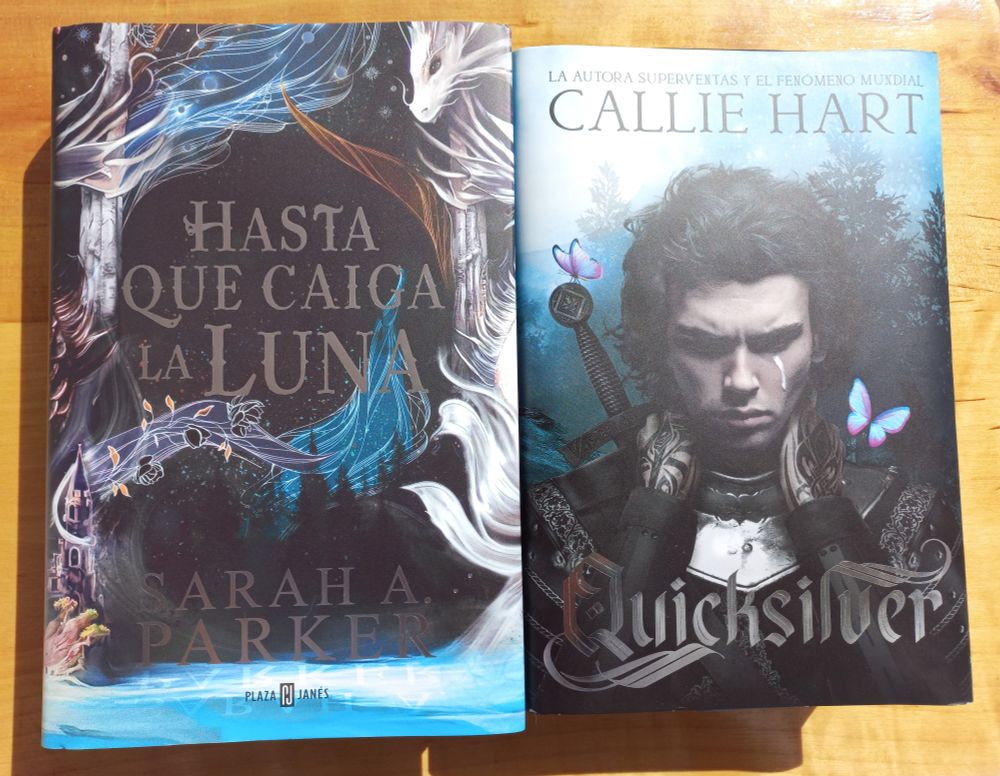 The special editions of the Hasta Que Caiga la Luna and Quicksilver books side by side on a wooden surface.
