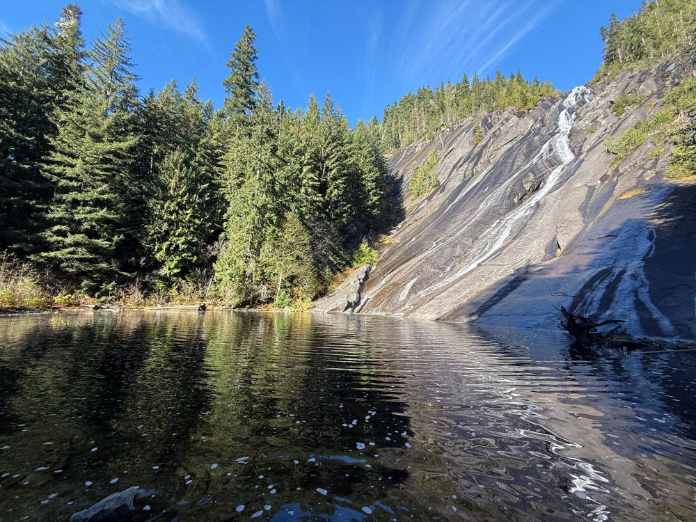 A picture of a waterfall with a small pond and trees on the side.