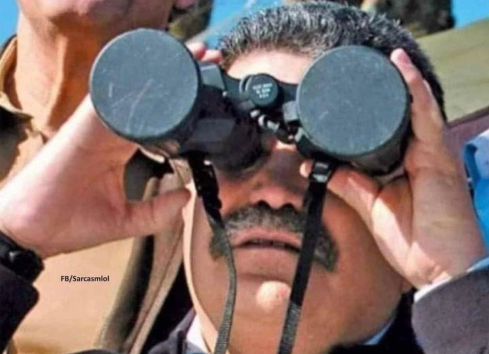 Maduro or someone who looks like him using binoculars with the covers on the lenses still