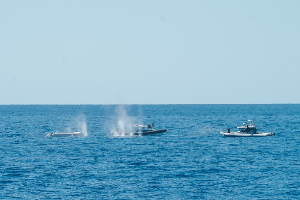 Zwei Boote der libyschen Küstenwache befinden sich neben zwei Schlauchbooten. Es wird auf die Schlauchboote geschossen.