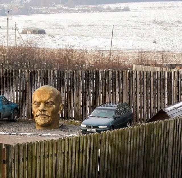 giant golden head of Vladimir Lenin in a fenced off car park 