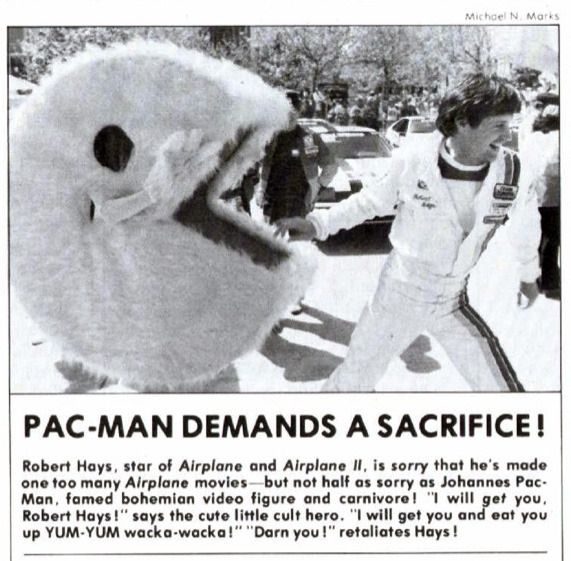 Pac-Man Demands a Sacrifice!"
Photo by Michael N. Marks for Vidiot, April-May, 1983  

Robert Hays, star of 'Airplane' and 'Airplane II' is sorry he's made one too many 'Airplane' movies-- but not half as sorry as Johannes Pac-Man, famed bohemian video figure and carnivore!  "I will get you, Robert Hays!" says the cute little cult hero.  "I will get you and eat you up YUM-YUM wacka-wacka!" "Darn you!" retaliates Hays!