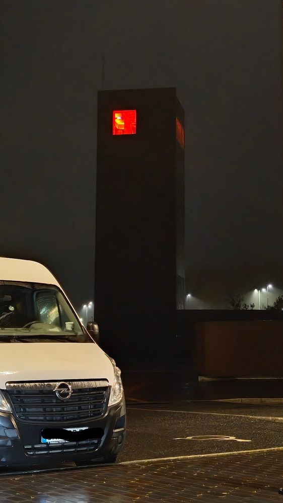 Et bilde av Solbergtårnet by night hvor toppen er opplyst i rød-oransje og får det til å se ut som et slag Barar-Dur på offentlig anbud