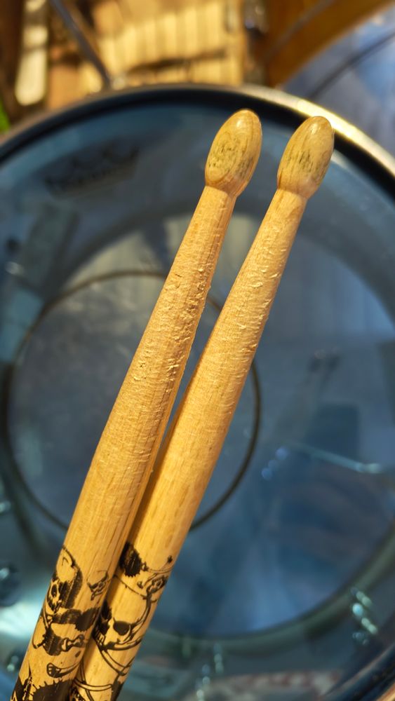 To hele, men synlig brukte, Tama 5A-stikker i eik foran en skarptromme.