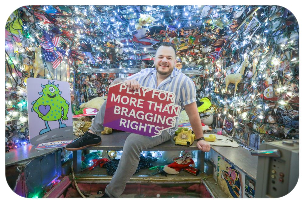 Ty screams in a Photo Booth holding a sign that says “play for more than bragging rights”