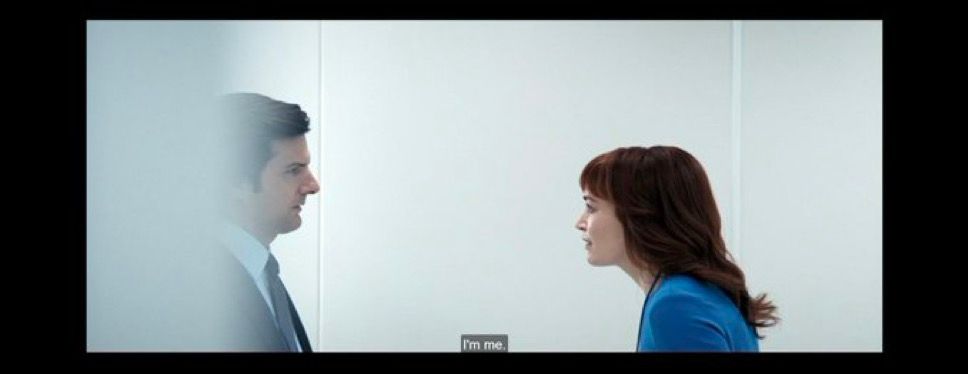 A shot from severance with mark and Helly against a gray background with a wall blurring the left side, making mark appear to be fading