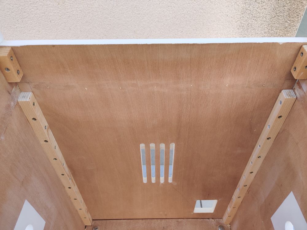 Inside of a small wooden arcade candy cab showing a line of glue residue and bits of wood going across the back side mostly removed.