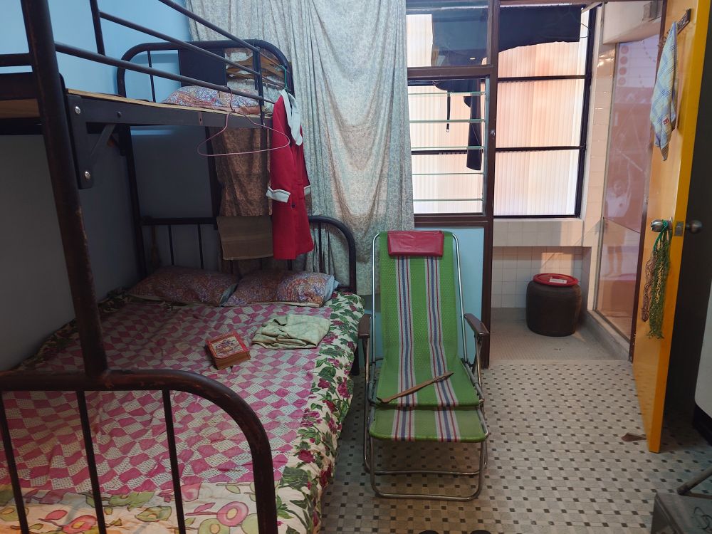 香港の歴史資料館、美荷楼生活館の展示写真。70年代〜90年代の個人宅展示。二段ベッドと簡易ベッド、床はレトロなタイル。