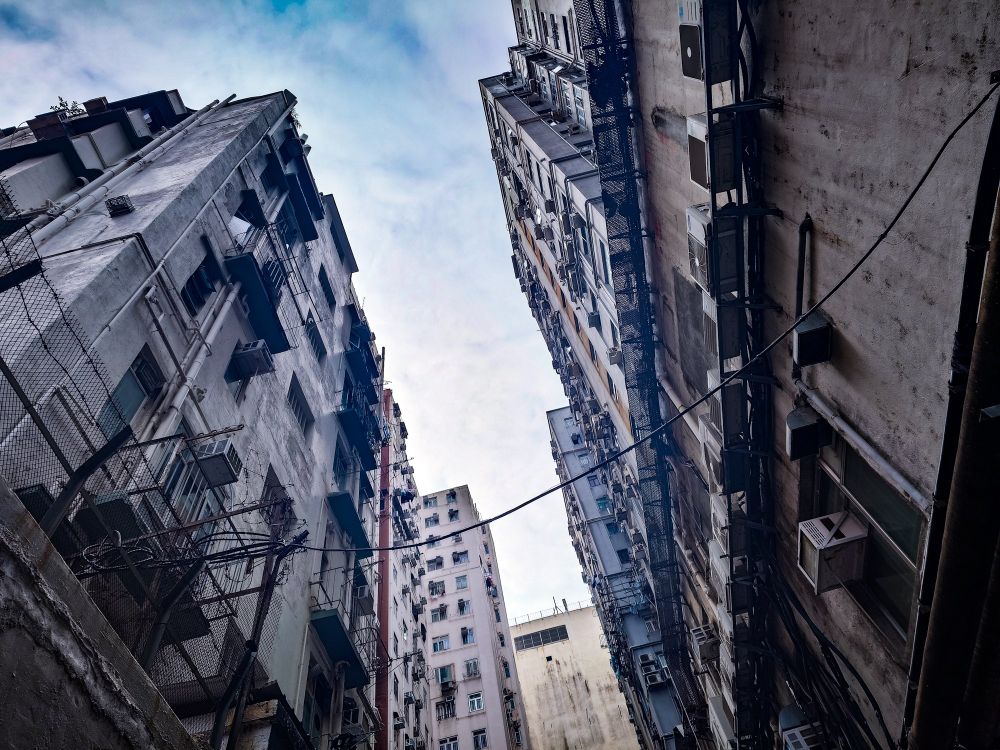 無骨なビルが両側に建っているところを見あげた写真。