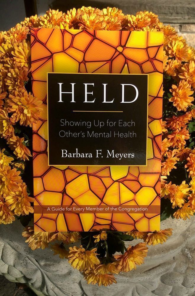 The book Held on top of some yellow-orange mums.