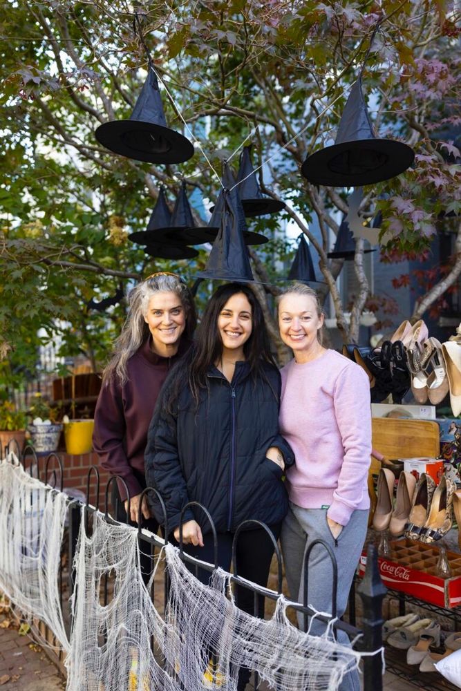 Three friends pose in front of their yard sale, October 25, 2025.