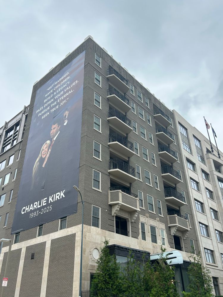 Wider shot of a poster depicting Charlie Kirk and his wife 
