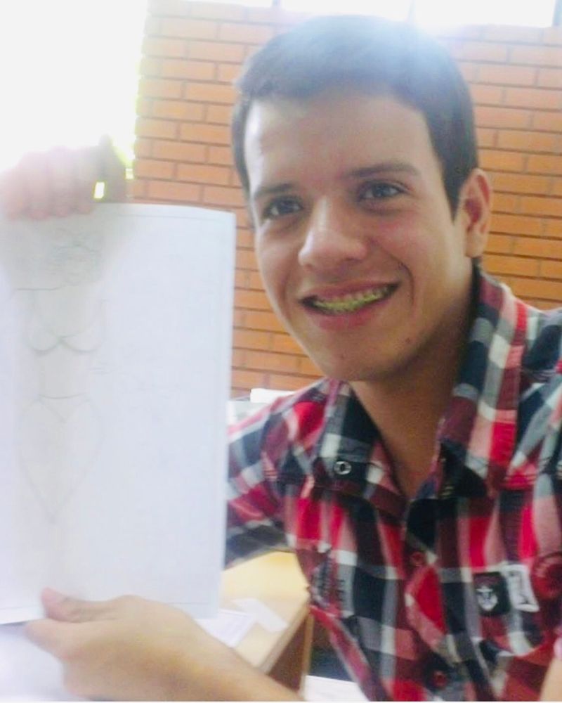Andry José Hernández Romero, from a few years ago, holding up a drawing of a costume he designed for his town’s Three Kings festival. 