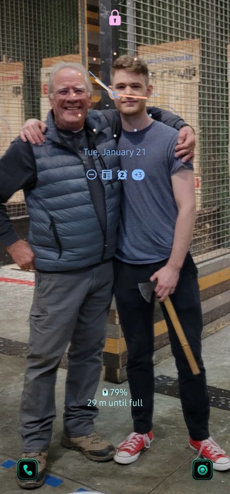 Two grown men, posing for a photo. One is holding a throwing axe and wearing red shoes.