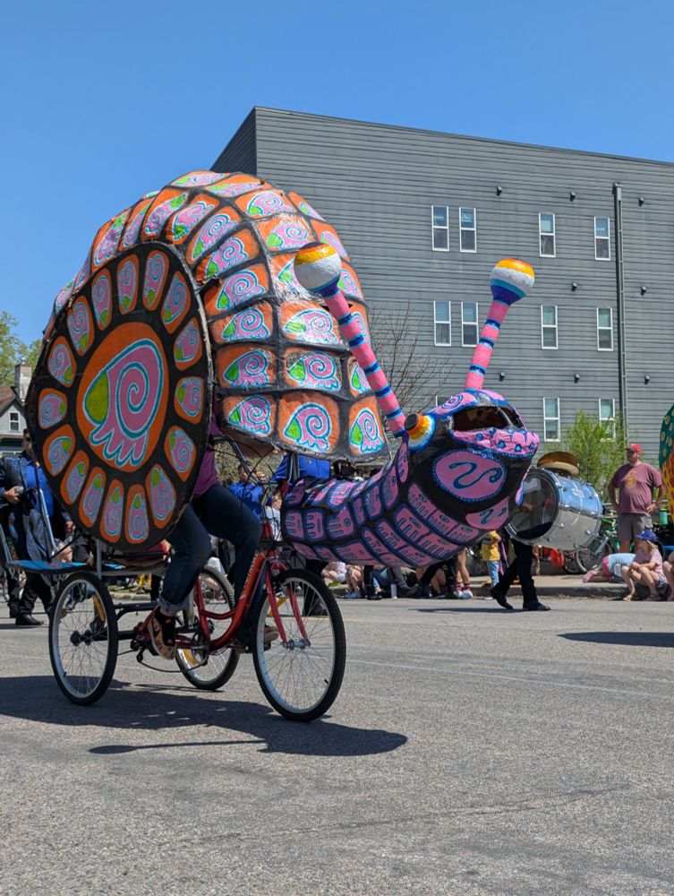 A beautifully painted snail built around a tricycle makes its way down the May Day parade 