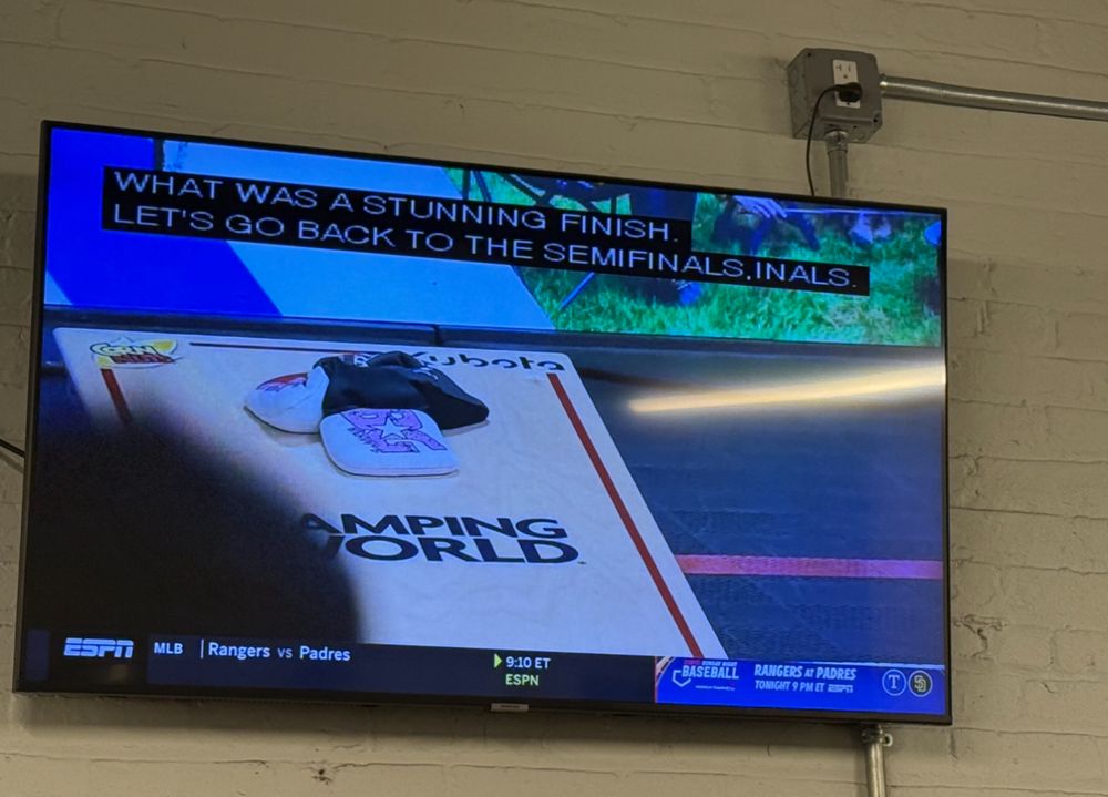 A cornhole board with several cornhole sacks on it on the TV