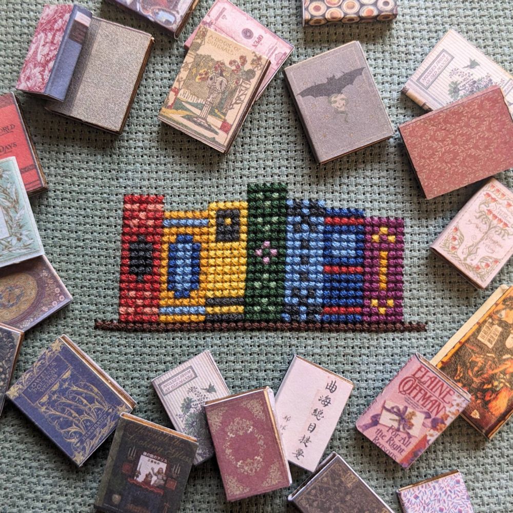 A sneak peek at a cross stitch pattern. Shows a shelf with a row of colorful books