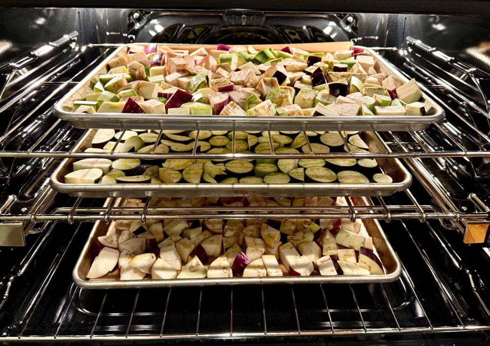 Three loaded trays of chopped eggplant slid into the oven filling all the racks and ready for roasting.