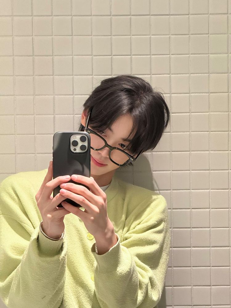 hanjin mirror selfie in thick black glasses and a green sweater