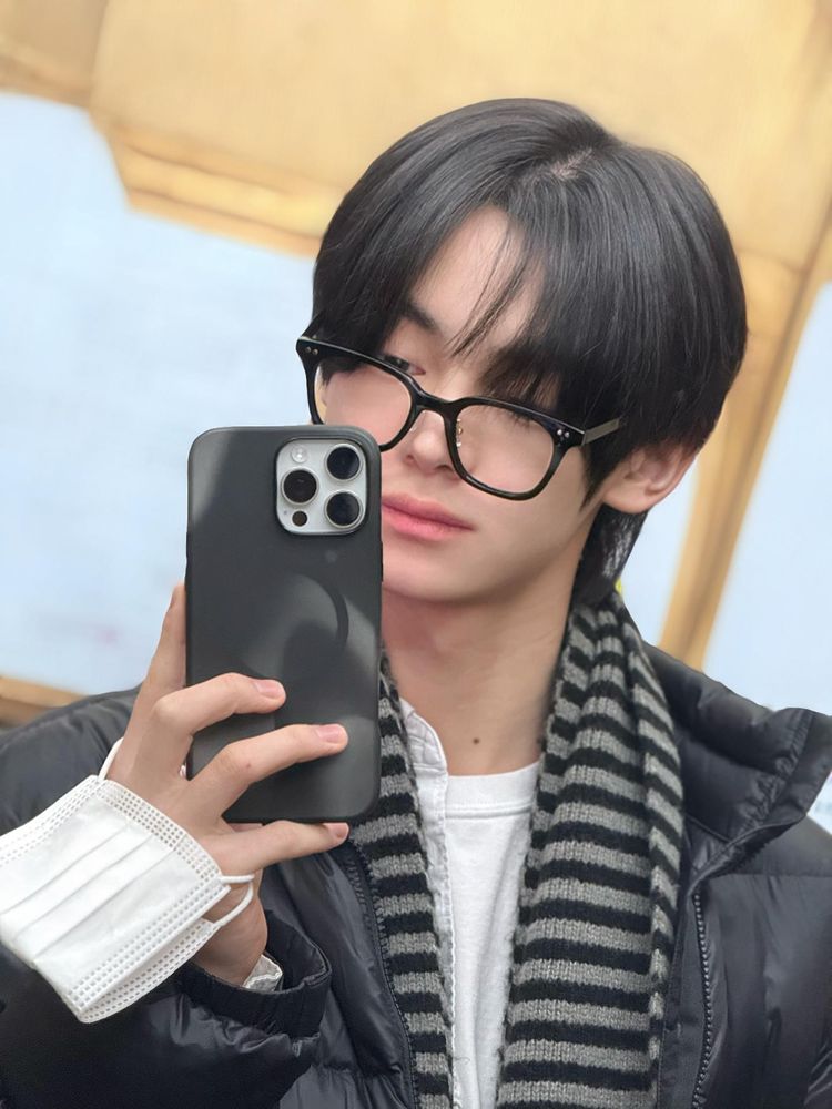 hanjin mirror selfie in a black coat, striped scarf and black glasses