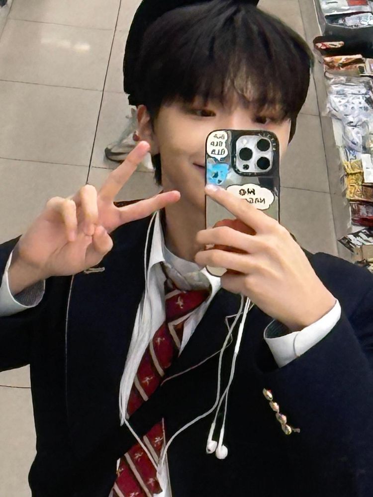 woonhak mirror selfie. he is doing a peace sign. 