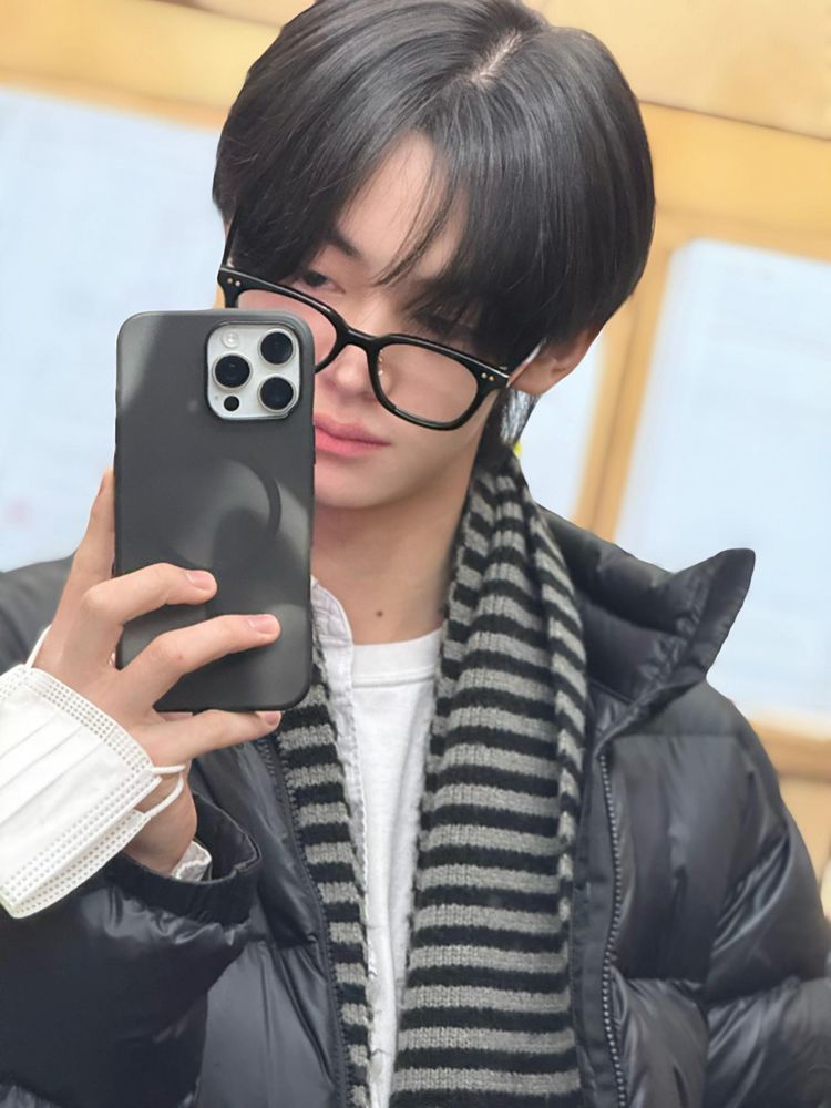 hanjin mirror selfie in a black coat, striped scarf and black glasses