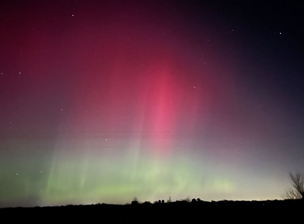 An aurora event, with a green glow underneath a wide swath of hot pink.
