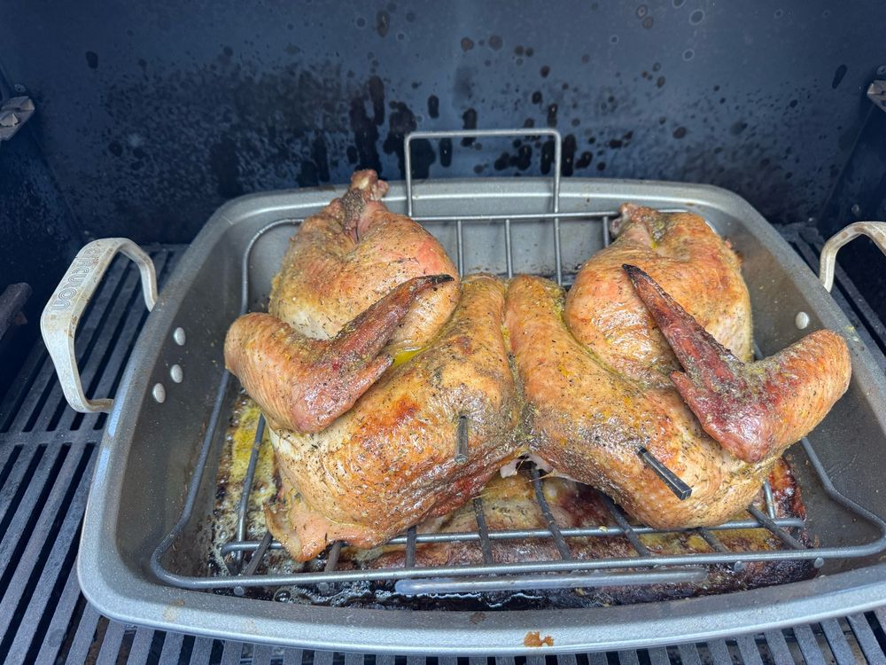 Spatchcock turkey in a pan inside a charcoal grill. 