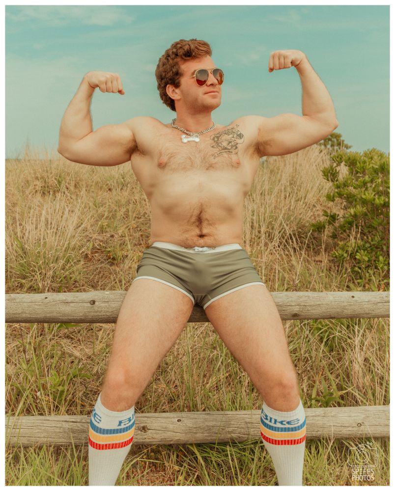 A picture of my friend sitting on a wooden bench, shitless and flexing at the camera. 