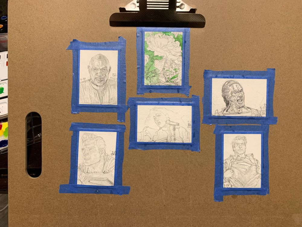 A series of six different 2.5x3.5 inch sketchcards are taped up with blue painter’s tape on a drawing board.
 
Captain Sisko from a front view, his face partially in shadow, drawn 7-31 LW.

A detailed pencil drawing of a rose surrounded by leafy foliage, a wash of green watercolor already painted in, and by the petals of other roses that are cropped just out of frame only partially visible, drawn 8-7 LW.

In landscape view is a bust portrait of Chapelle Roan in front of a microphone in a puffy-sleeved dress looking away from the viewer towards the left. Her card has the least amount of detail and is not shaded in. Drawn 7-27 2025.

Garak from Deep Space Nine, looking excited and happy in a striped shit with an open vest with jazz hands only partially visible drawn 8-3 2025.

 And two sketch card portraits of Superman, one is a front view of him pulling back a button-up shirt to reveal the Superman logo and the other card is a closer 3/4 view of him looking off to the left in his full uniform, both drawn 7-27 2025 LW.