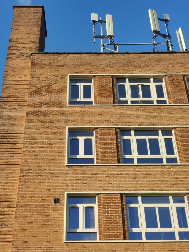 1950s brick building, vaguely Moderne style, with decorative horizontal bands of brickwork and recessed brick pillars between windows.
