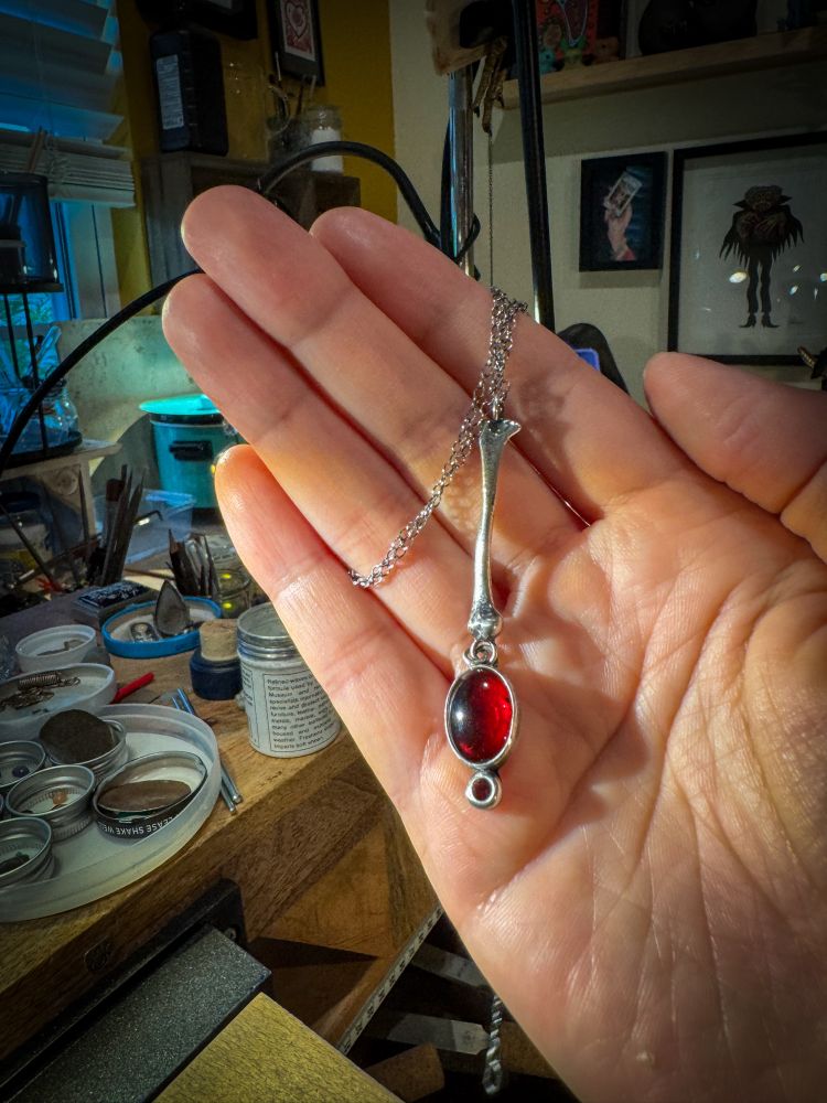 Pendant with a silver bone and a large oval garnet, paired with a small faceted garnet 