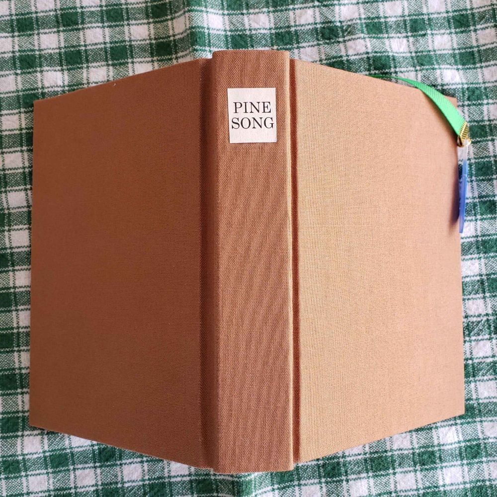 A different view of the book showing the paper label on the spine. The label says "Pinesong"
