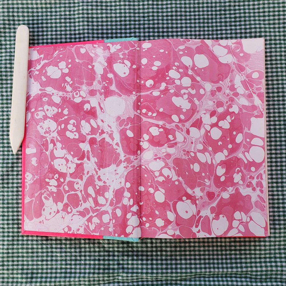 The endpaper of the book. Its handmarbled with a pink stone pattern.