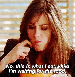 Jordan McDeere from Studio 60 chewing and waving a spoon around, with gif subtitle 'No this is what I eat while I'm waiting for the food'.