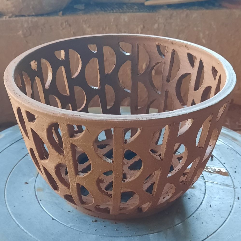 A red clay pot with alternating semicircles carved from its sides