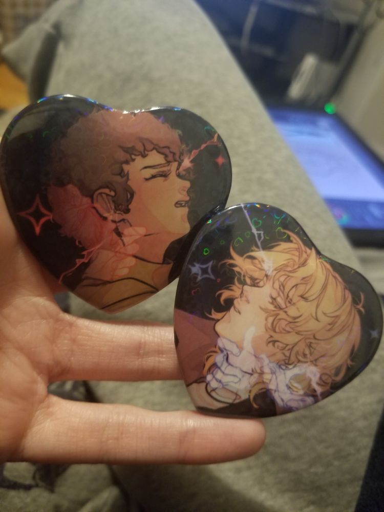 Photograph of a pair of pin back buttons featuring fanart of Amuro Ray and Char Aznable.