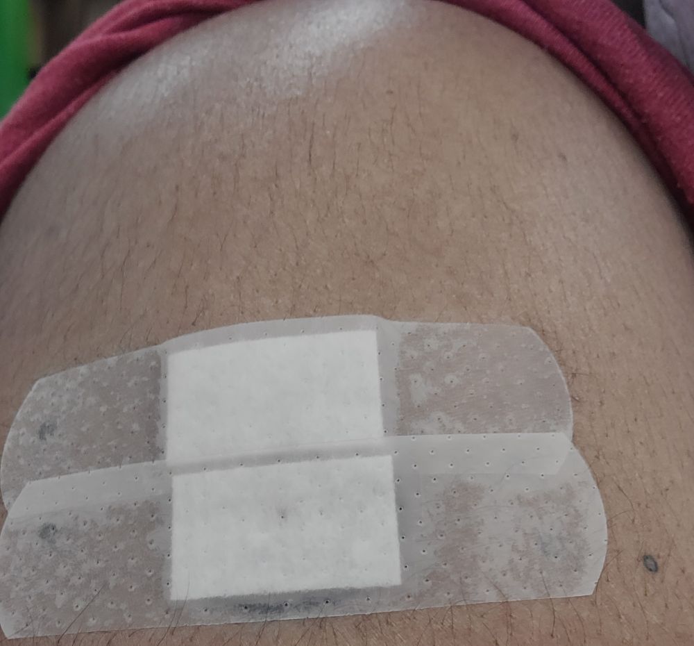 My (Black! don't you forget it!) arm with a partially visible red rolled up sleeve and two bandages (one on top of the other) a couple inches down from my shoulder. 

Flu and Covid shots