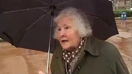 Old Scottish woman with short white hair in a green coat holding an umbrella. She’s about to say something awesome.