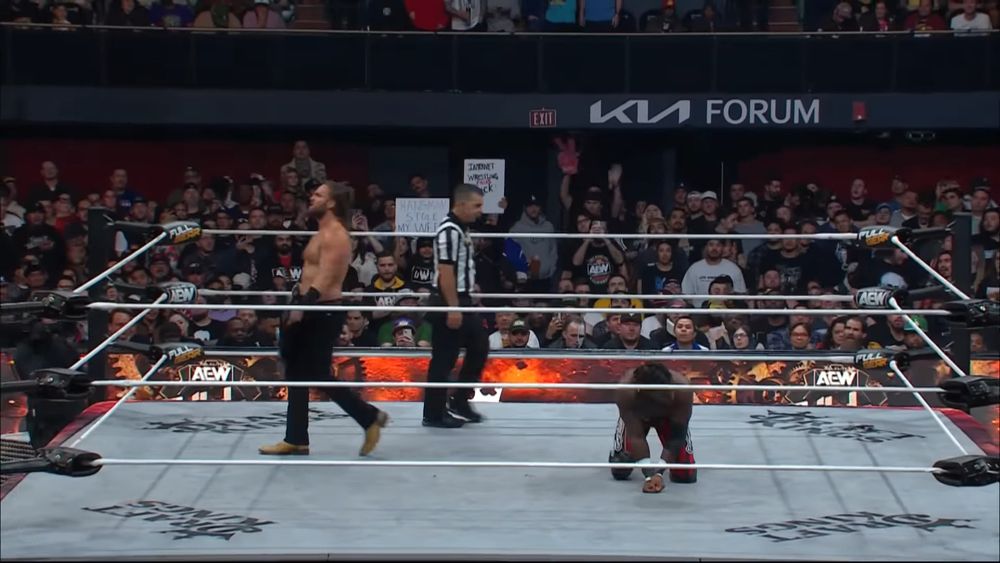 Hangman Adam Page in the ring during his Texas Death Match with Swerve. He has a tiny cartoon cowboy hat photoshopped onto his head.