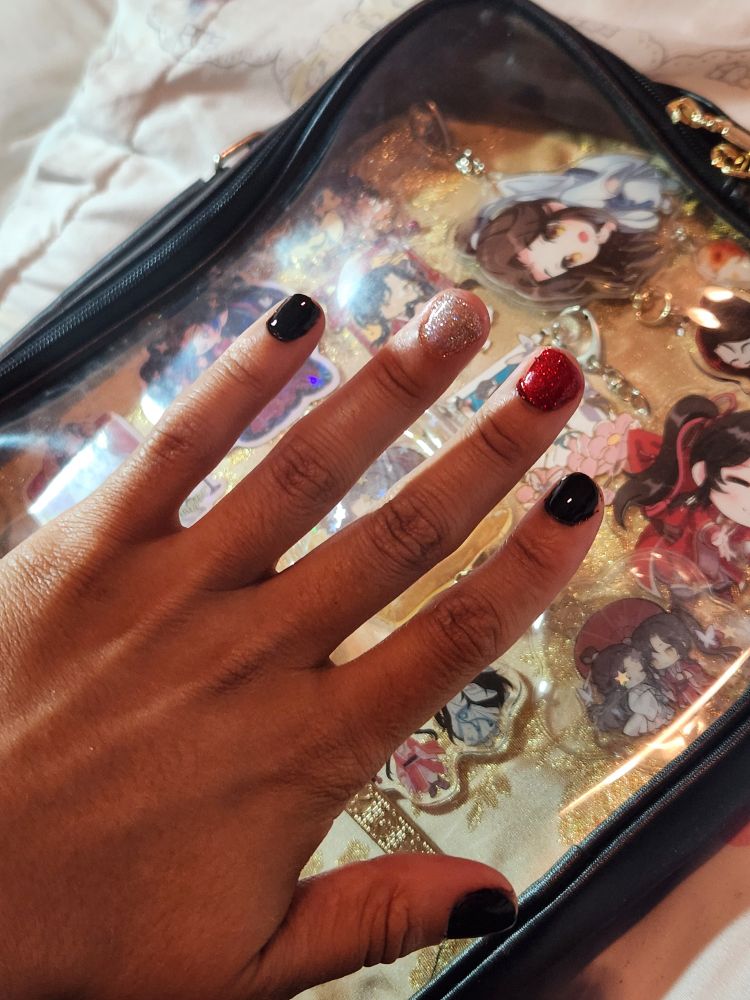 a hand with nails painted black, silver and red nail polish