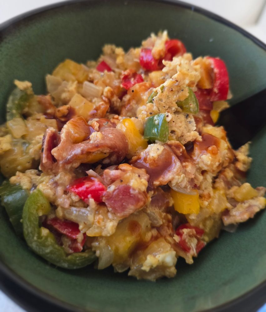 Pic of the egg scramble I made in a green & black bowl. There's white sweet potatoes, jalapeño, red and yellow peppers, onions, garlic, bacon, cheese, and eggs (w/a touch of half & half mixed into the eggs) 