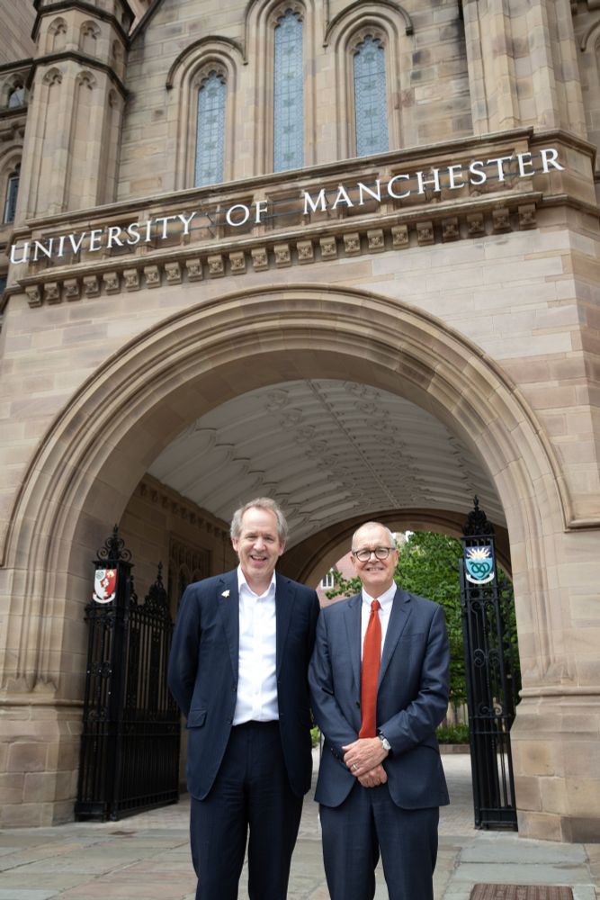 Duncan Ivison and Patrick Vallance smiling in front of the UoM arch, dressed smartly.