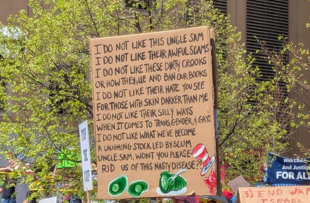 Sign that reads, "I do not like this Uncle Sam.  I do not like their awful scams.  I do not like these dirty crooks or how they lie and ban our books.  I do not like their hate, you see for those with skin darker than me.  I do not like their silly ways when it comes to transgender and gays.  I do not like what we've become, a laughing stock led by scum.  Uncle Sam, won't you please rid us of this nasty disease ?!" Green eggs and ham are drawn on the bottom.